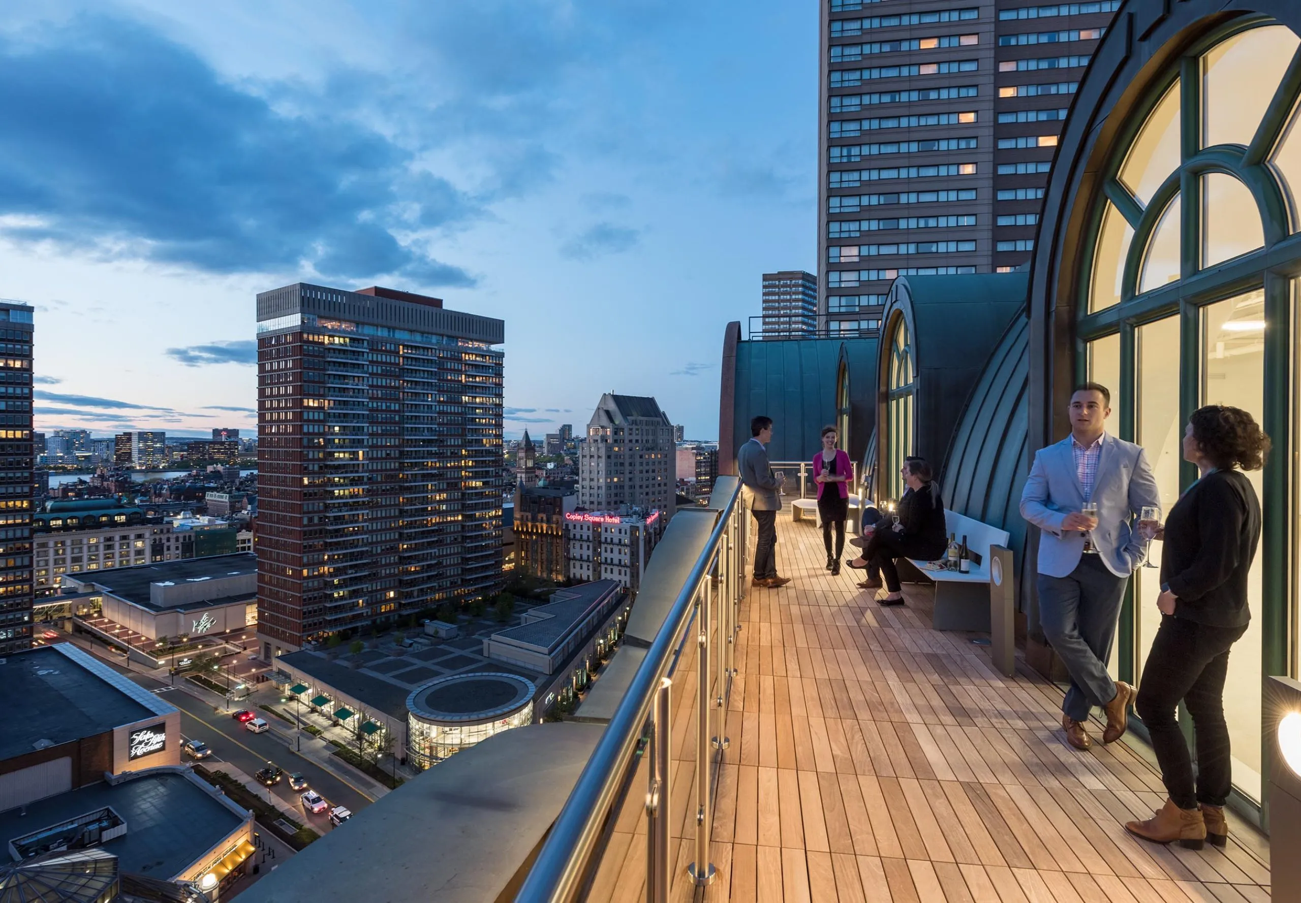 People sitting on balcony of office building with skyline in the background