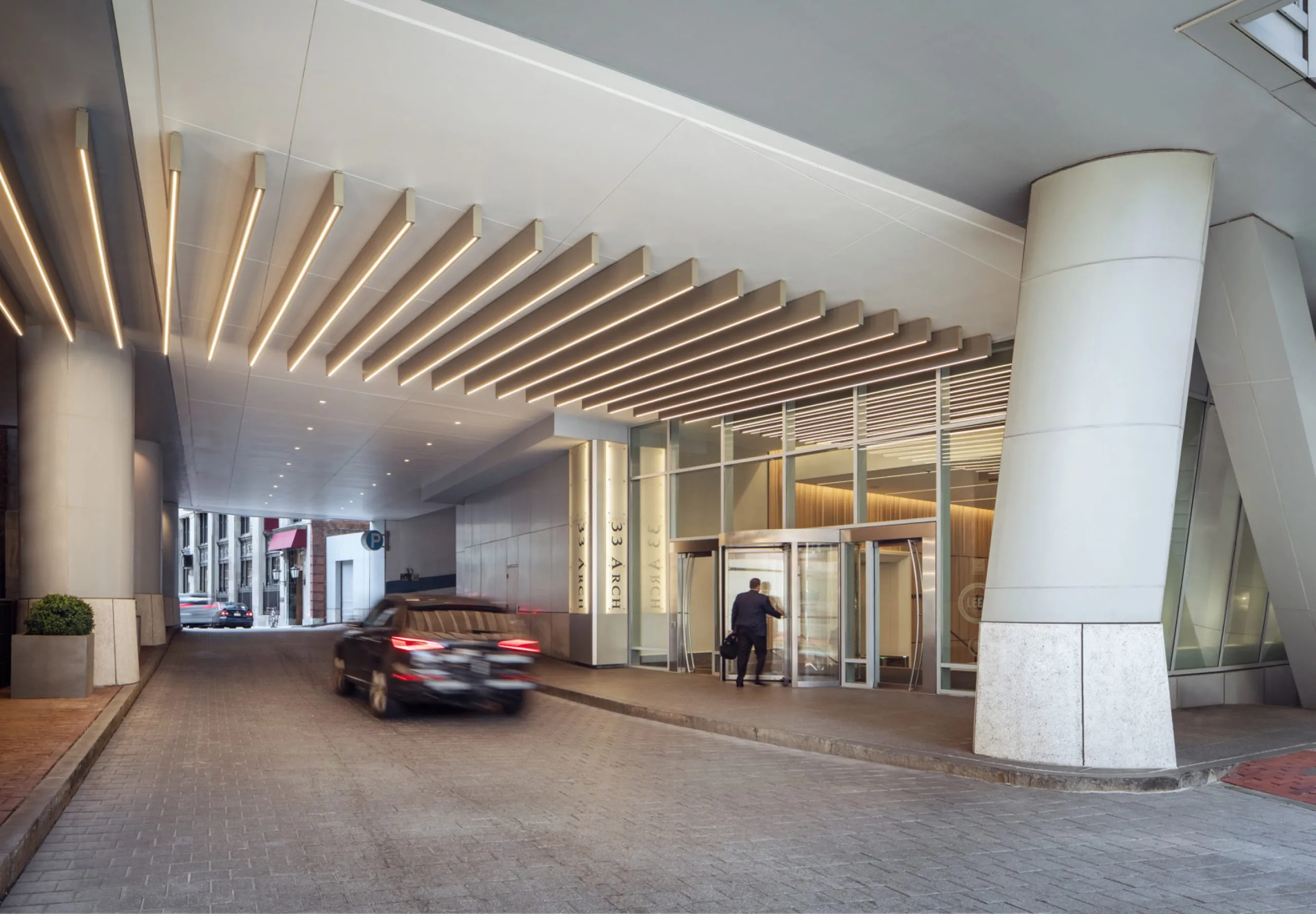 Cars driving on covered private road with entryway to office building