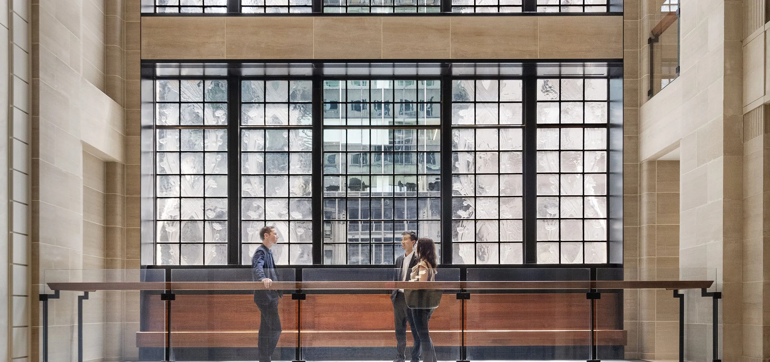 People talking on walkway with large windows in background