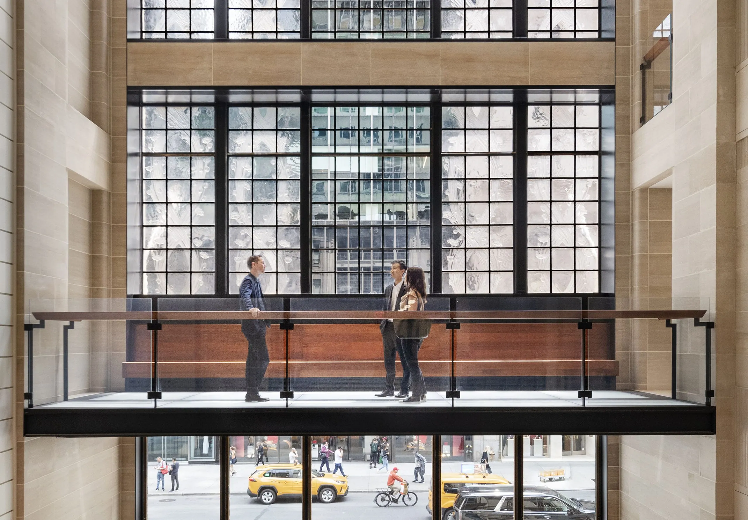 People talking on walkway with large windows in background