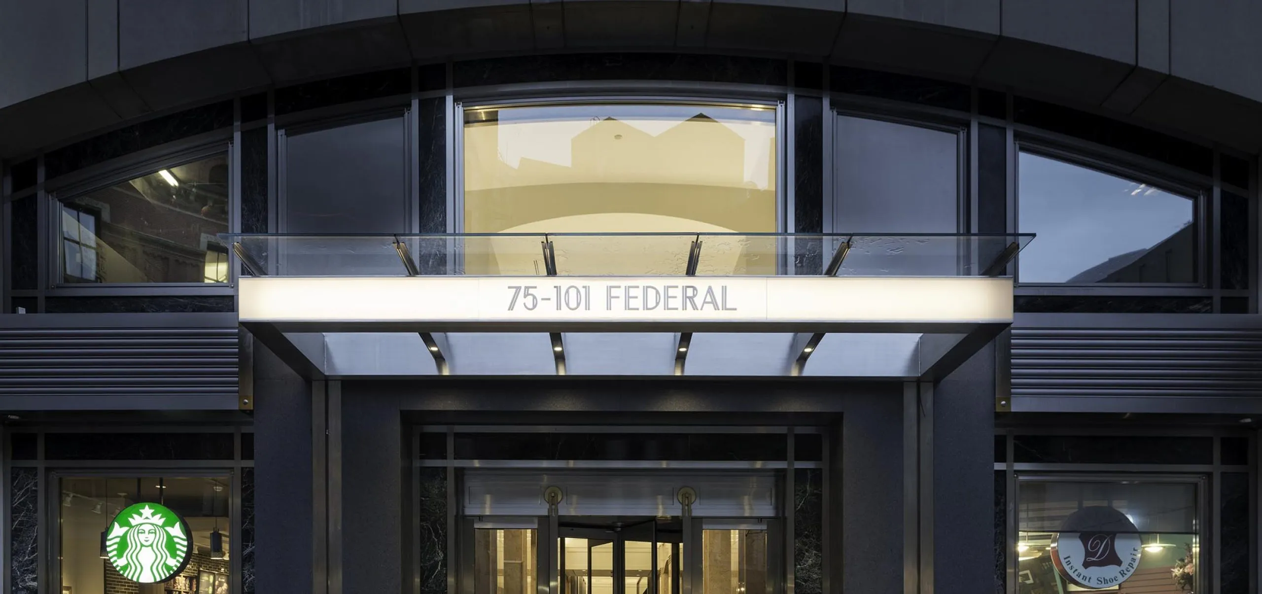 Exterior entry of apartment building with shops visible from front windows at 75-101 Federal street