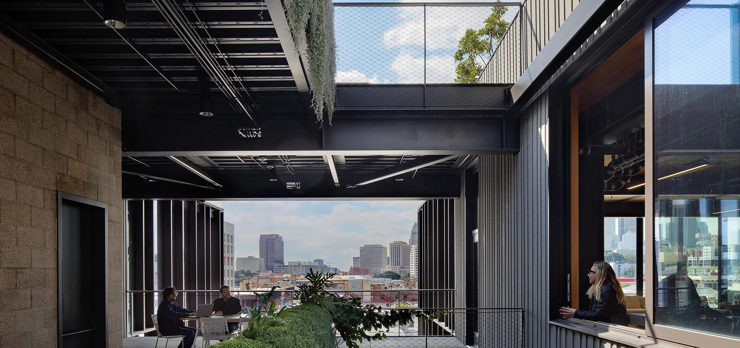 People sitting on multistory balcony with seating and at table and person looking out of large window