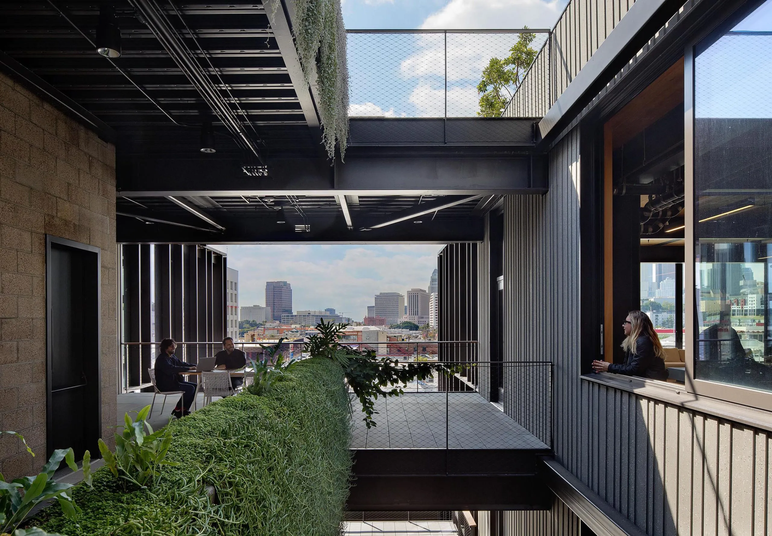 People sitting on multistory balcony with seating and at table and person looking out of large window