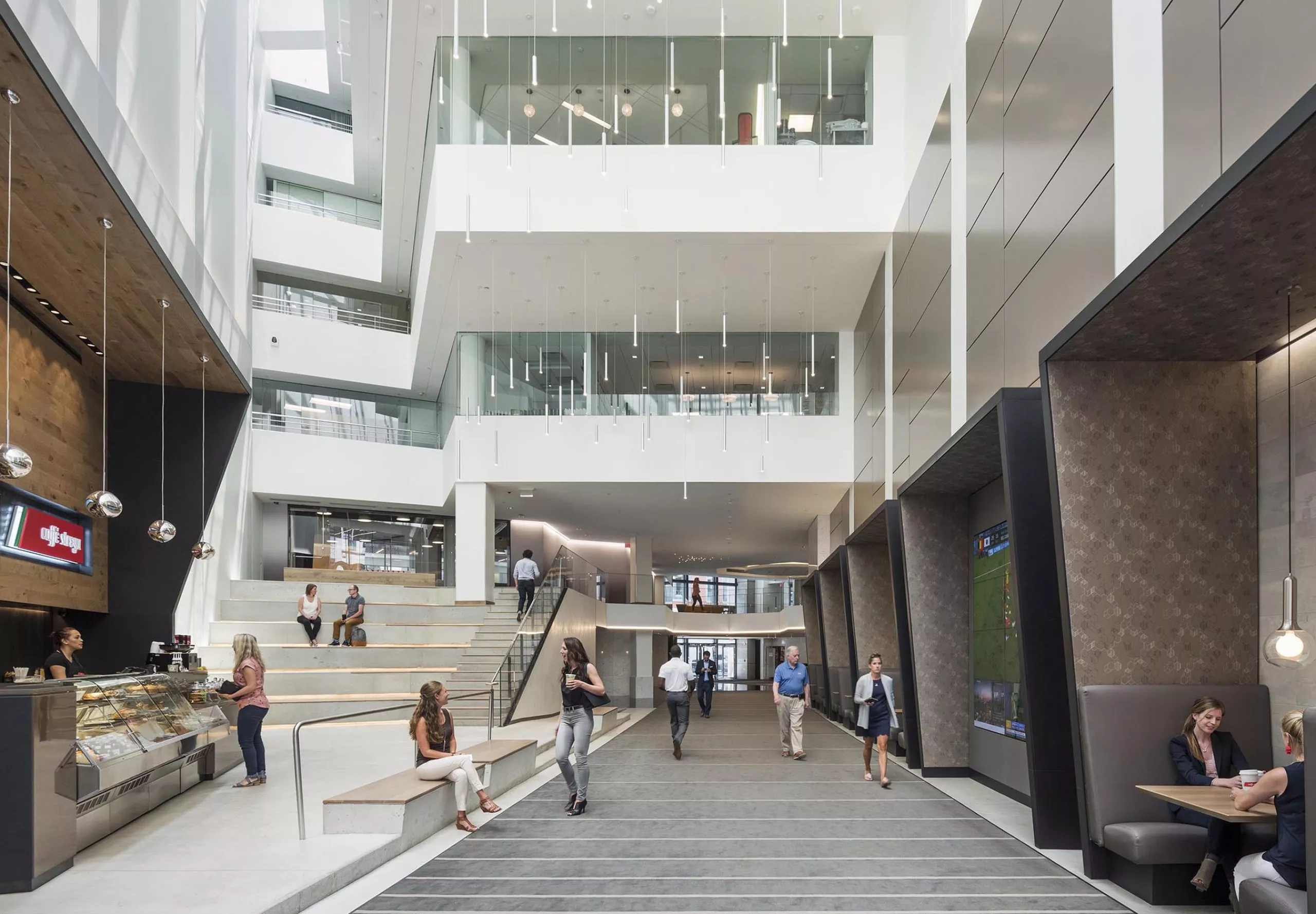 Open multistory interior of office building with indoor cafe and people walking around and talking