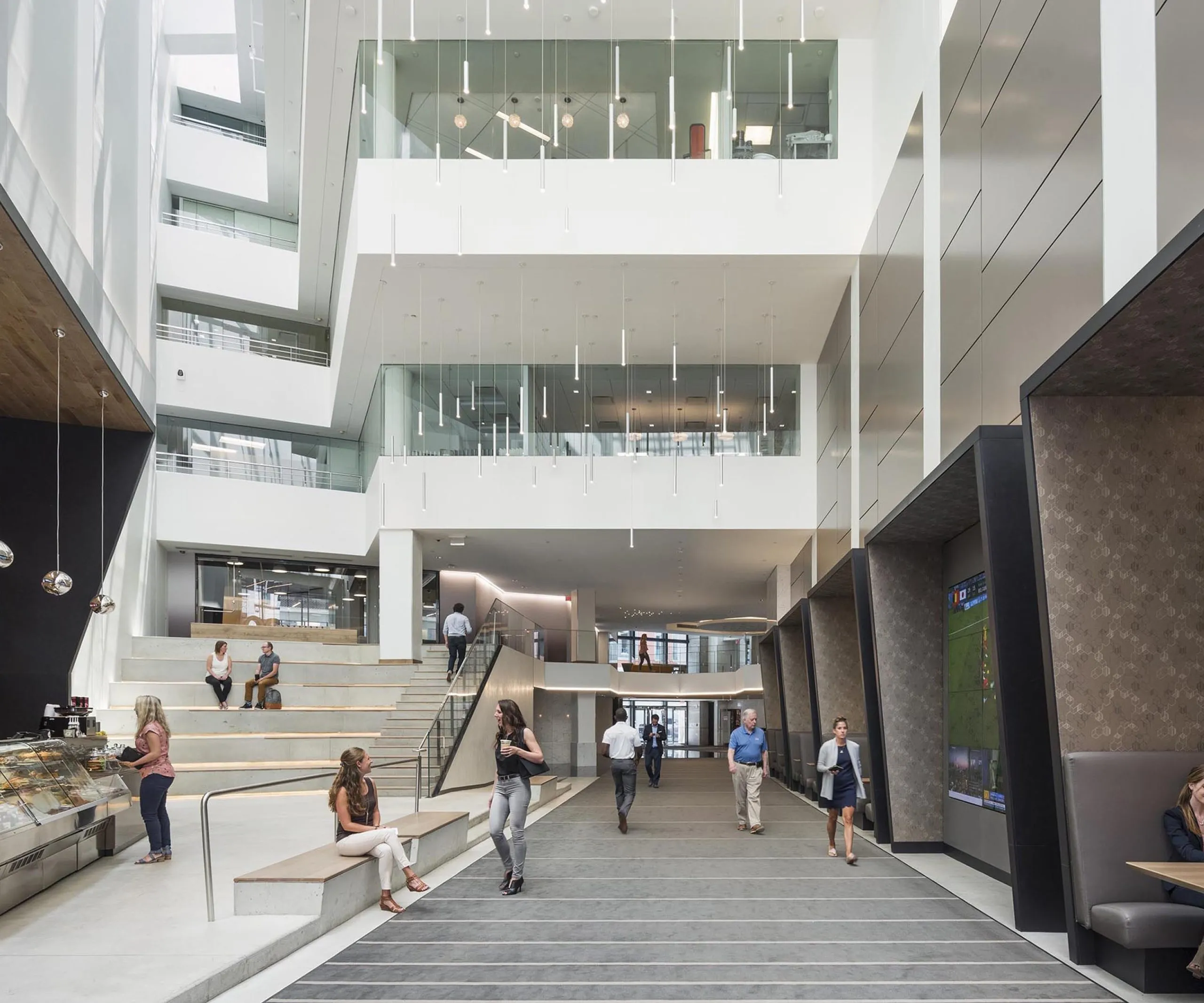 Open multistory interior of office building with indoor cafe and people walking around and talking