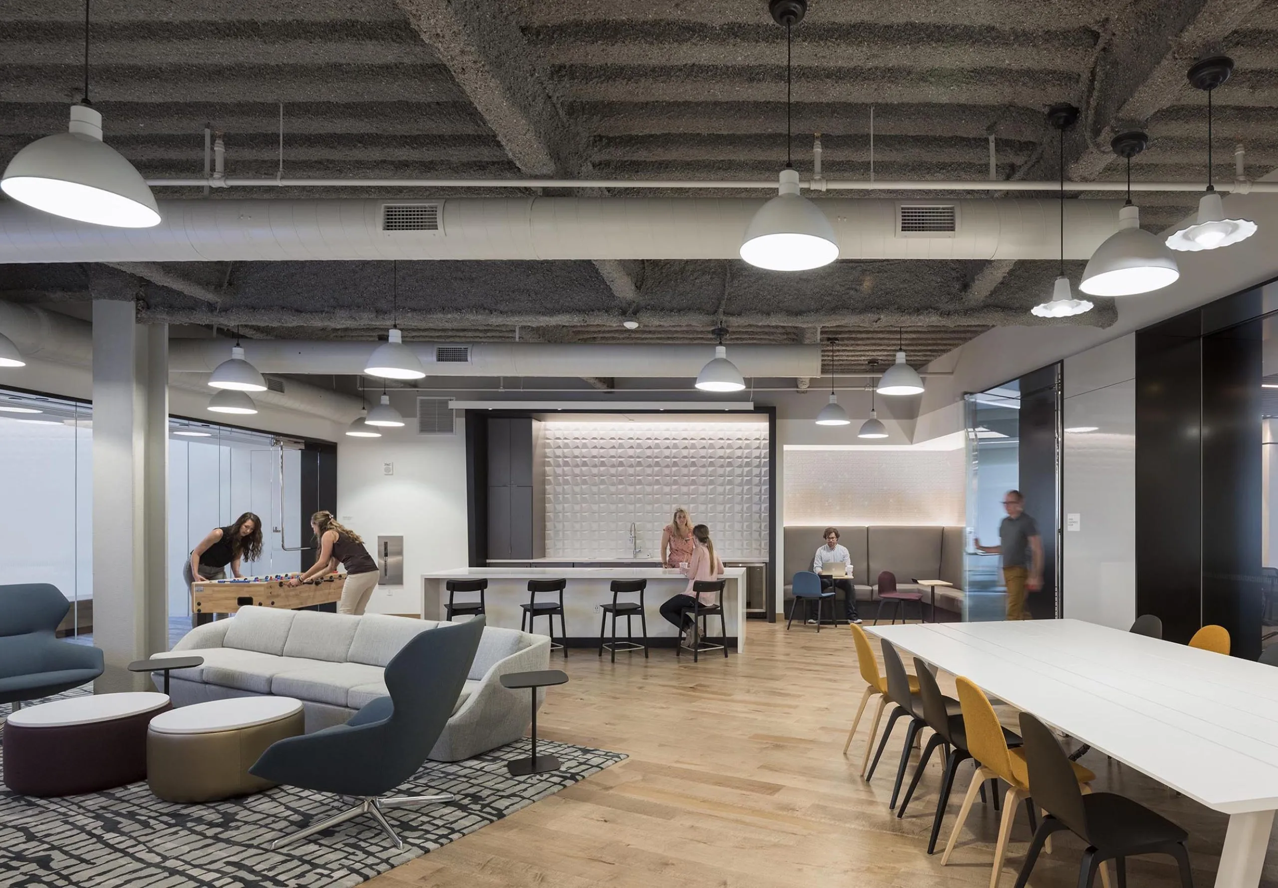 Communal space with kitchen, living room, dining room and foosball table in office building