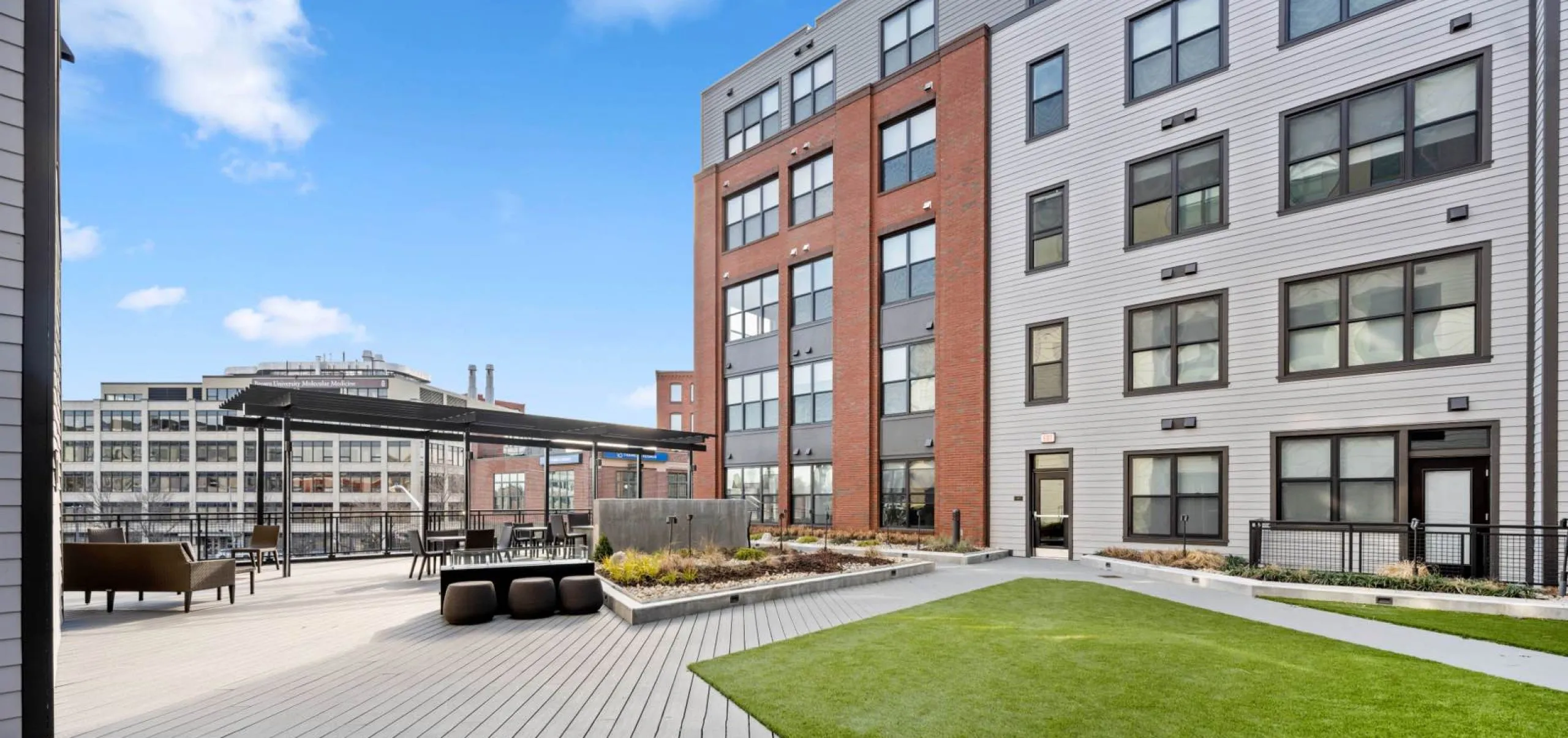 Outdoor seating area and grass patch in courtyard at Emblem 125 Apartment complex