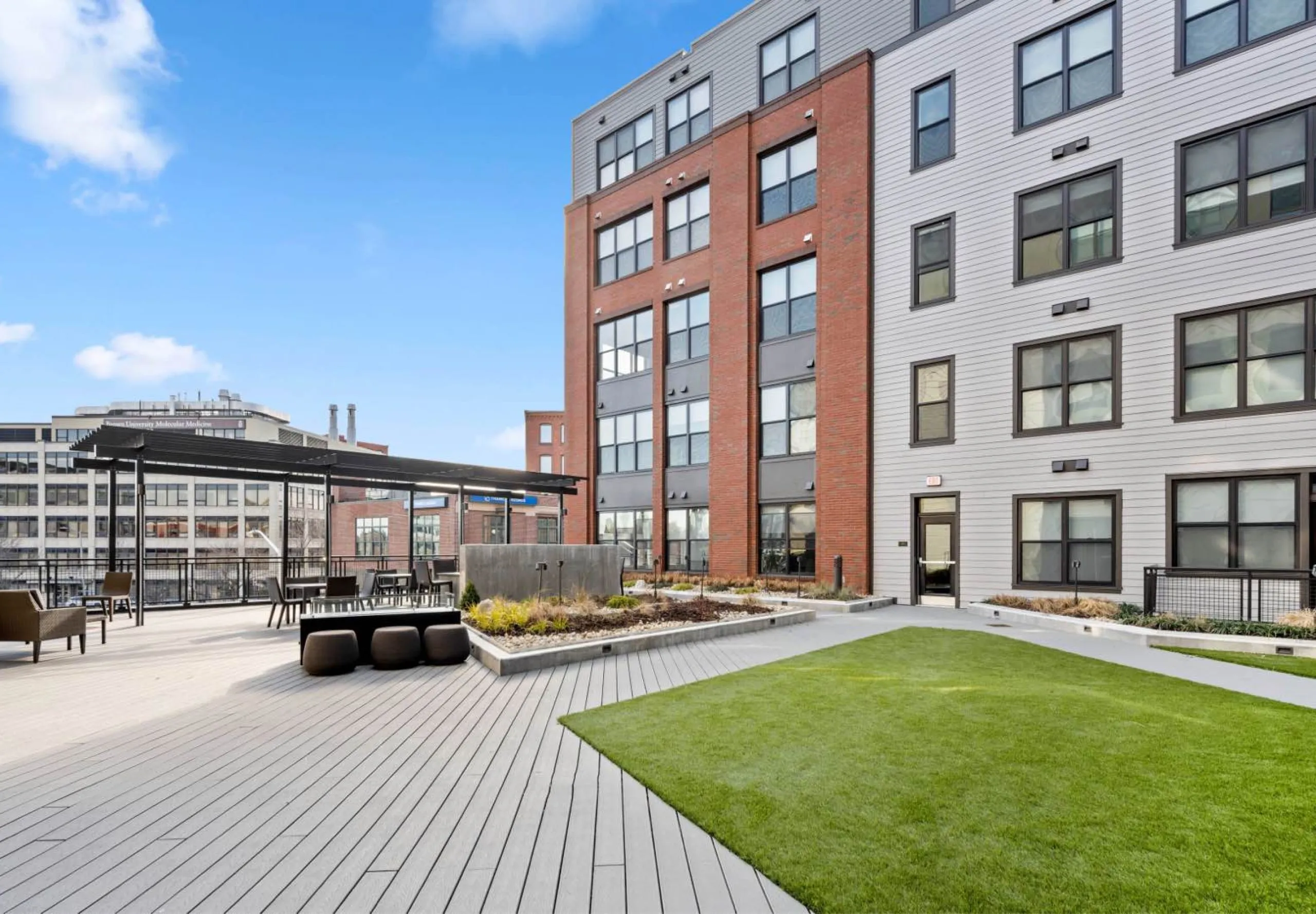 Outdoor seating area and grass patch in courtyard at Emblem 125 Apartment complex