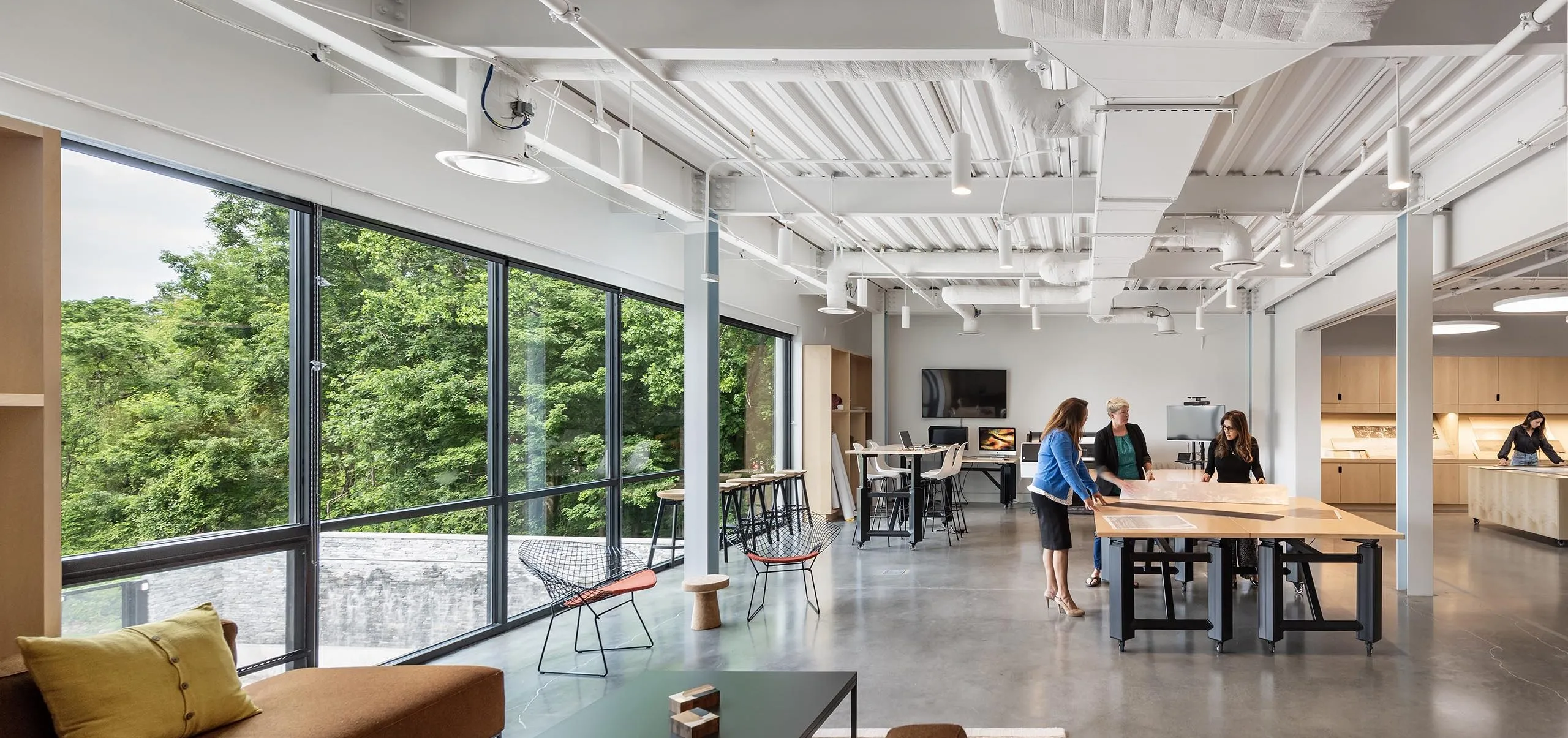 People looking at large diagrams on table in communal collaborative office space at HMTX Headquarters