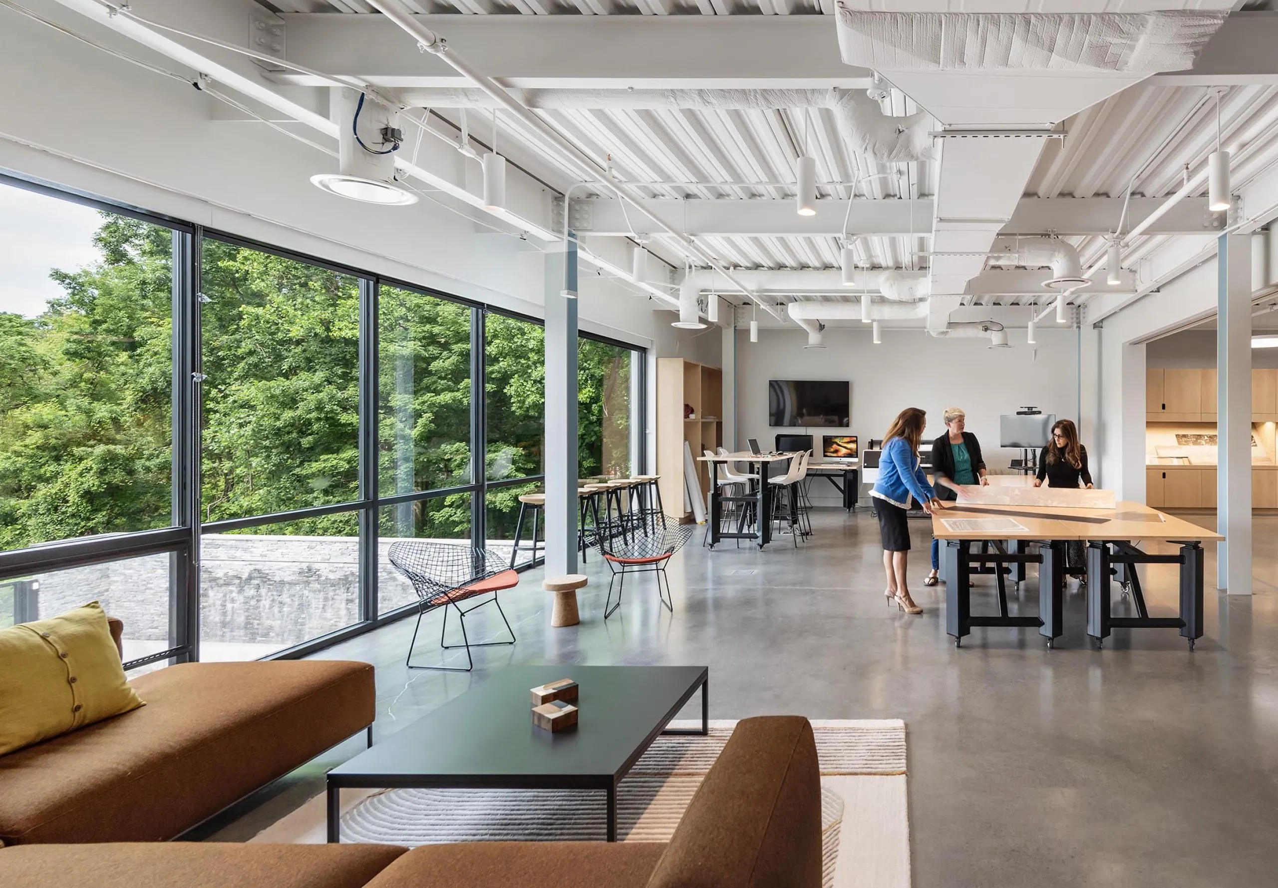 People looking at large diagrams on table in communal collaborative office space at HMTX Headquarters