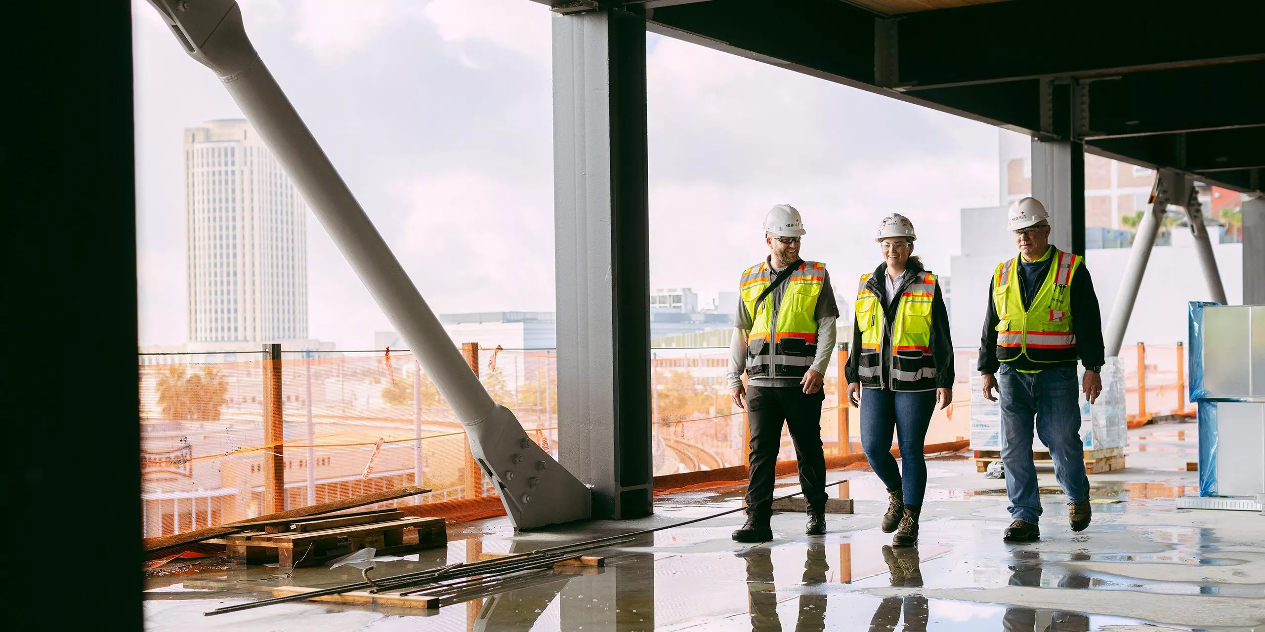 Three people in safety gear walking in a construction site