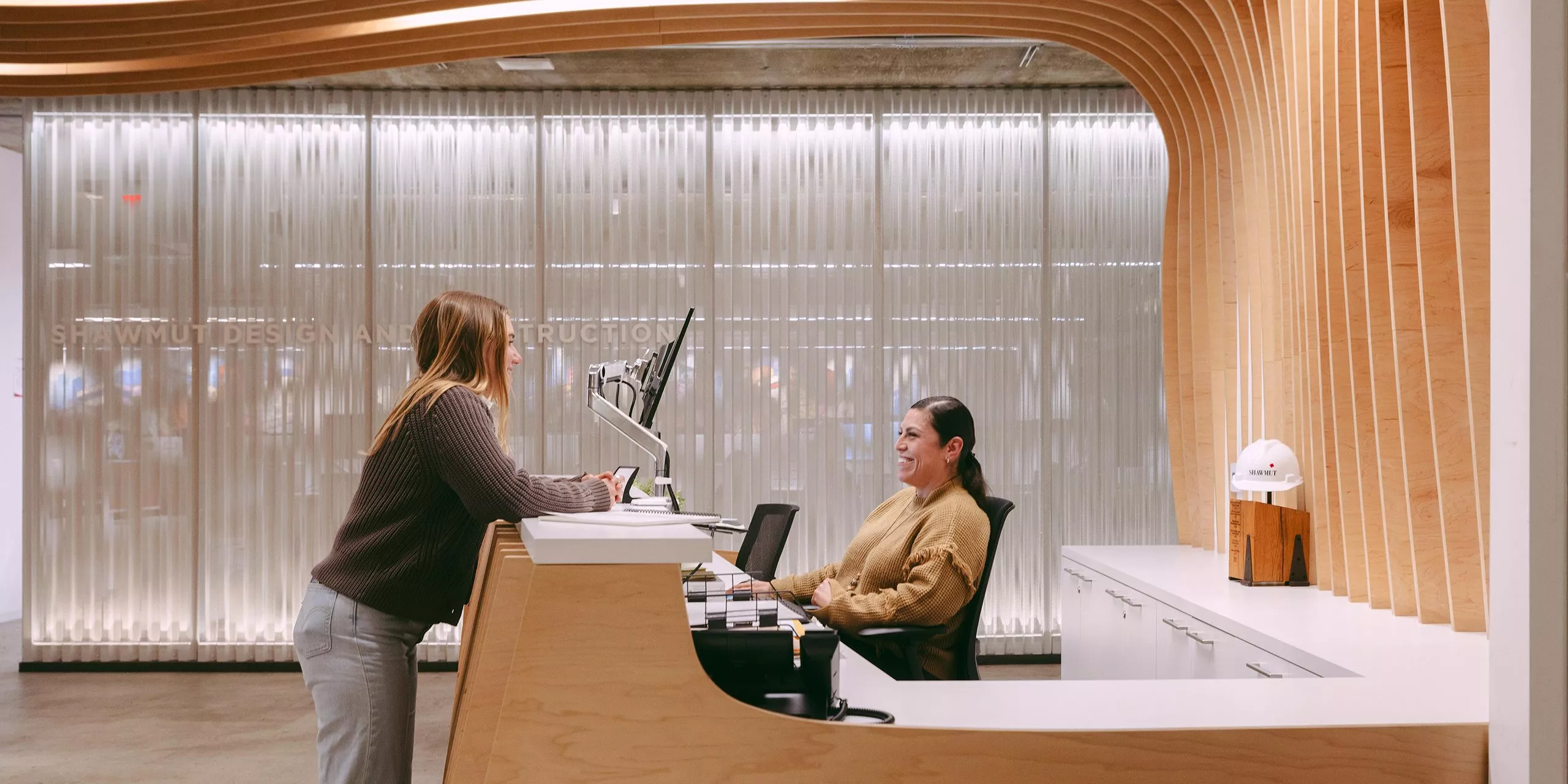 Person standing at front desk of Shawmut office speaking with receptionist