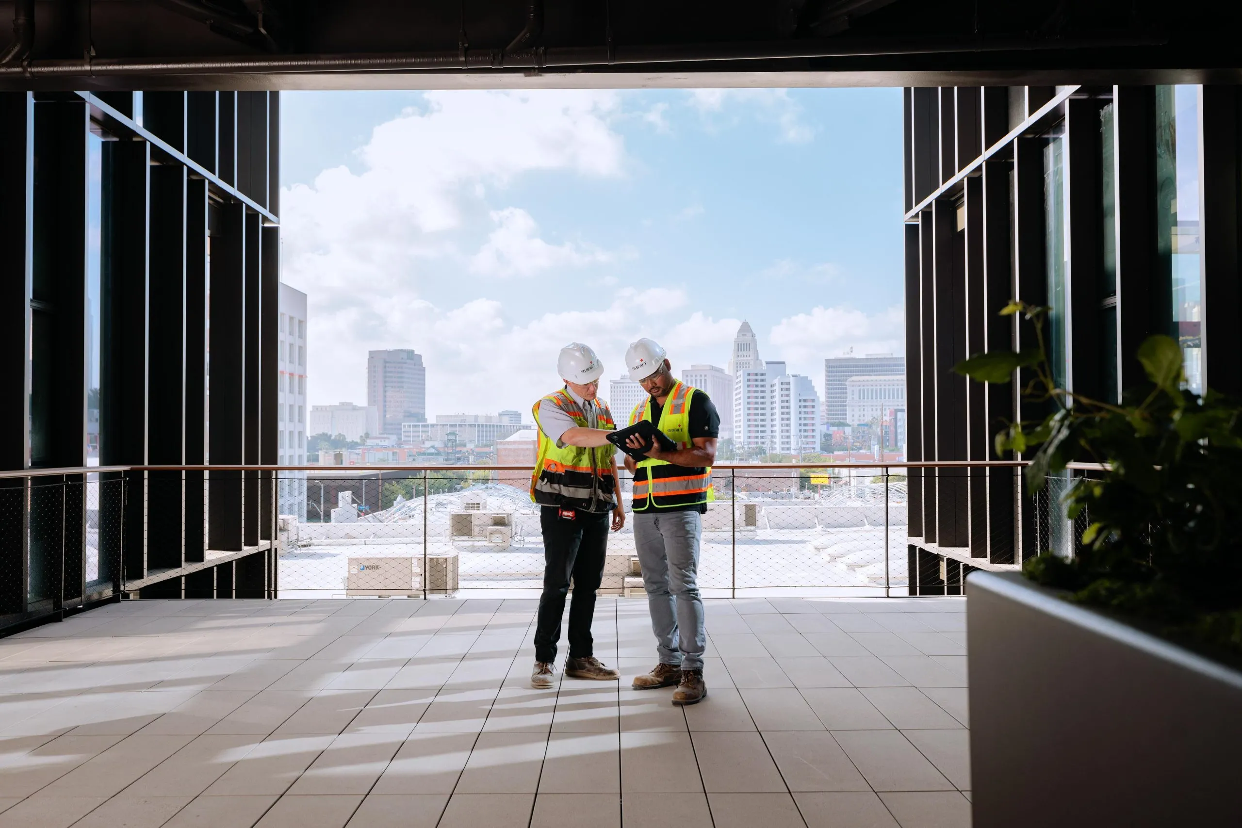 Two people in safety gear looking at a tablet