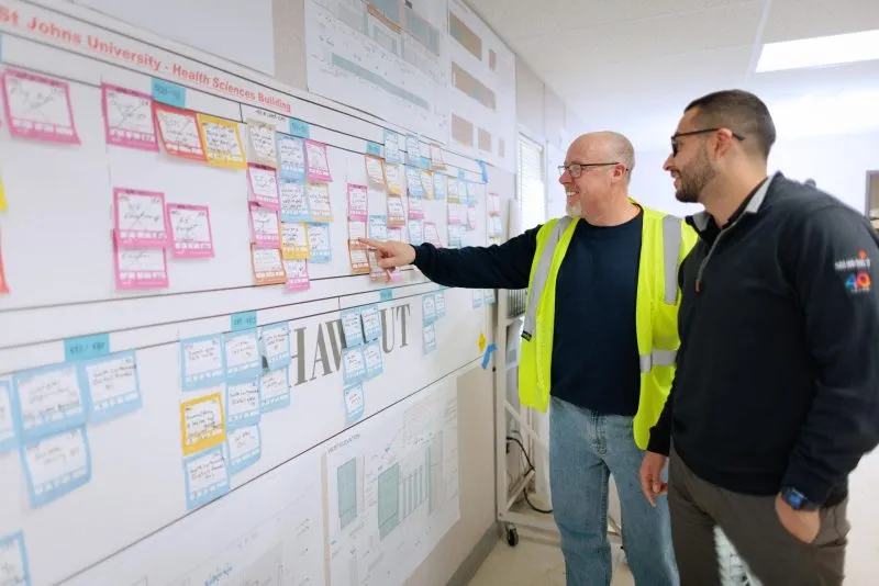 Two people looking at sticky notes on a white board