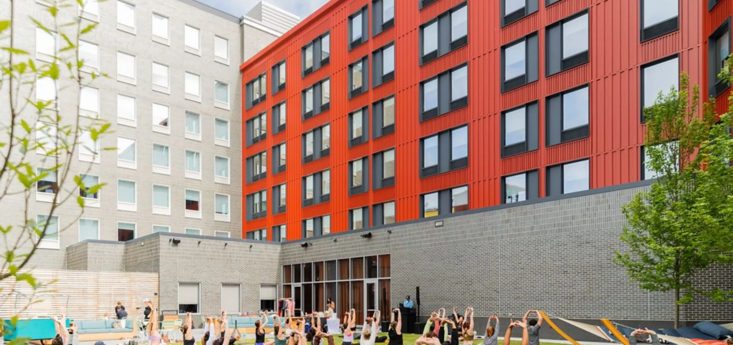 Exterior view of the Aloft Providence Downtown with people on the lawn doing yoga