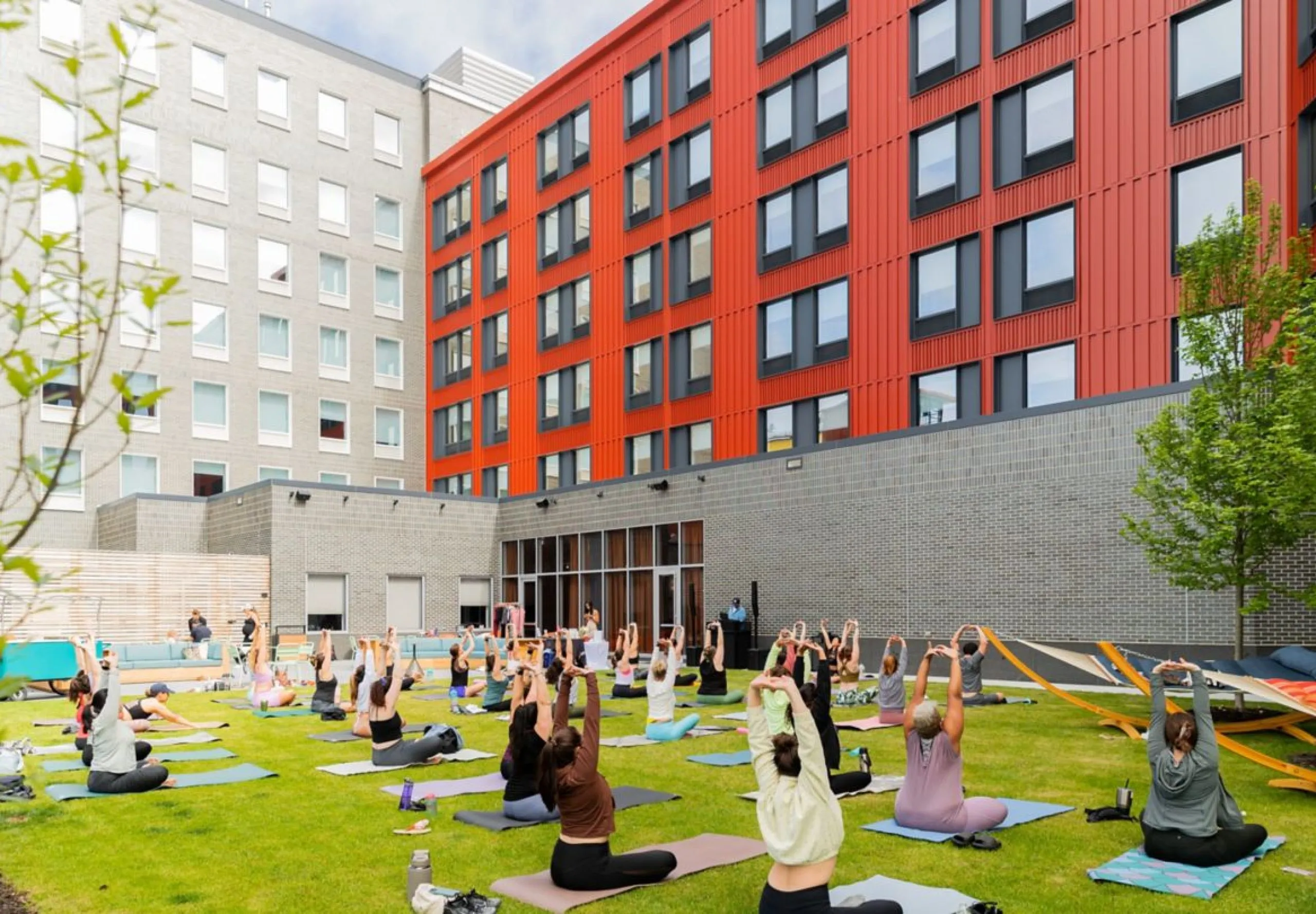 Exterior view of the Aloft Providence Downtown with people on the lawn doing yoga