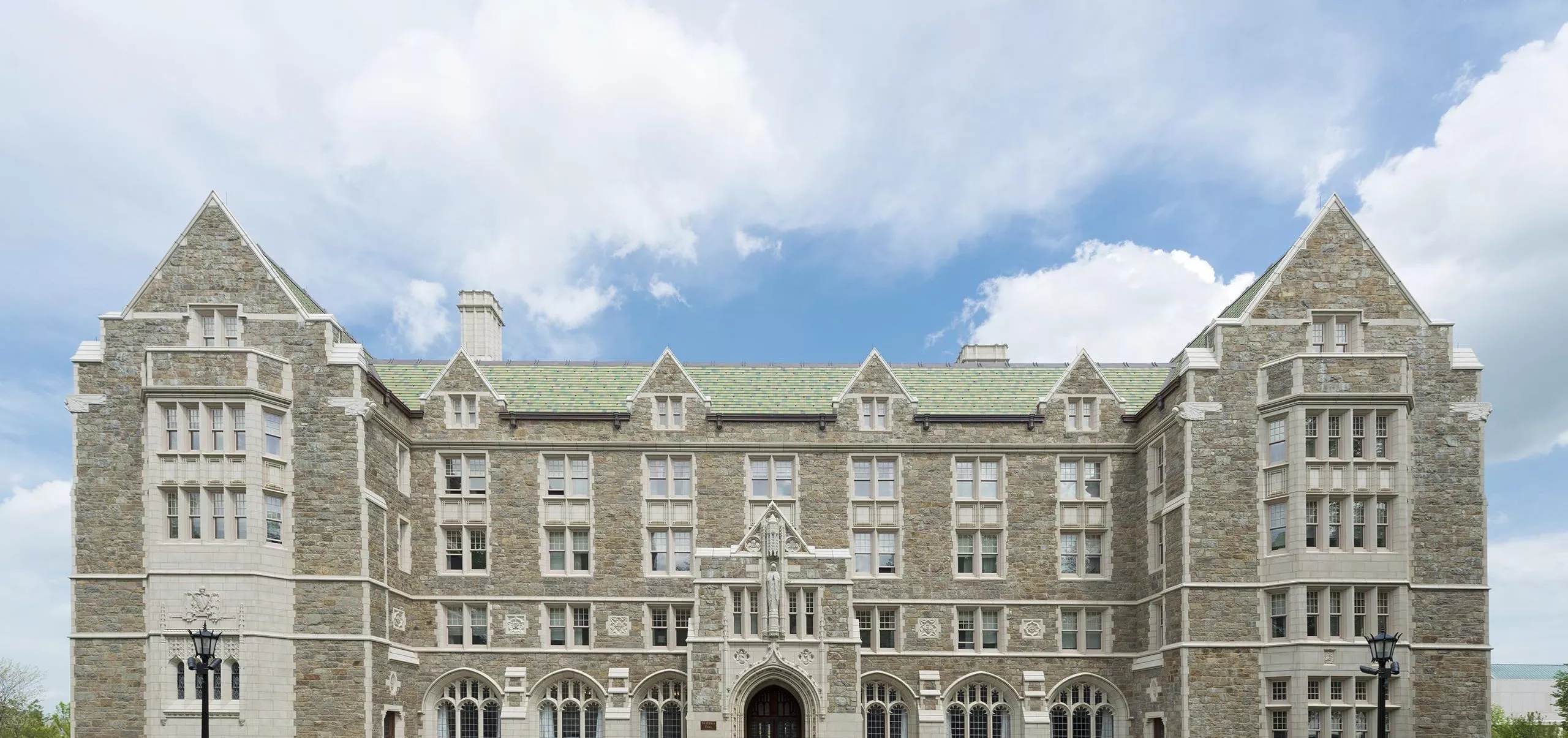 a large stone building with a green lawn with Boston College in the background