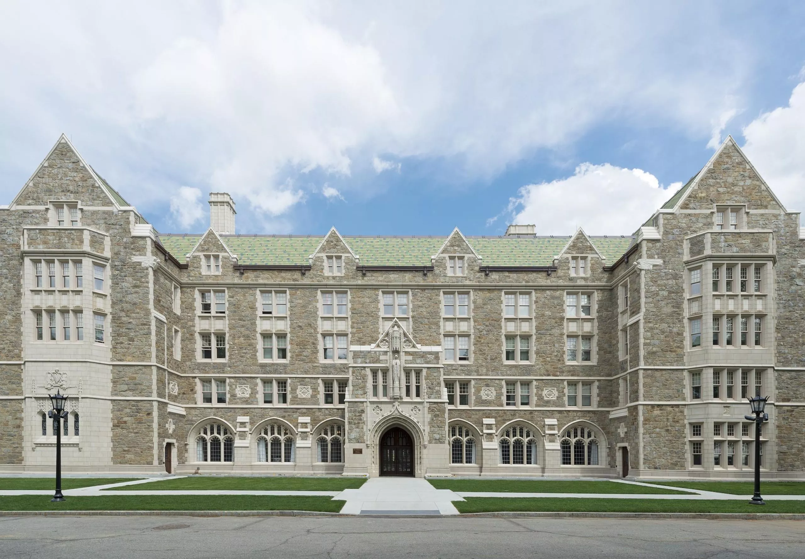 a large stone building with a green lawn with Boston College in the background