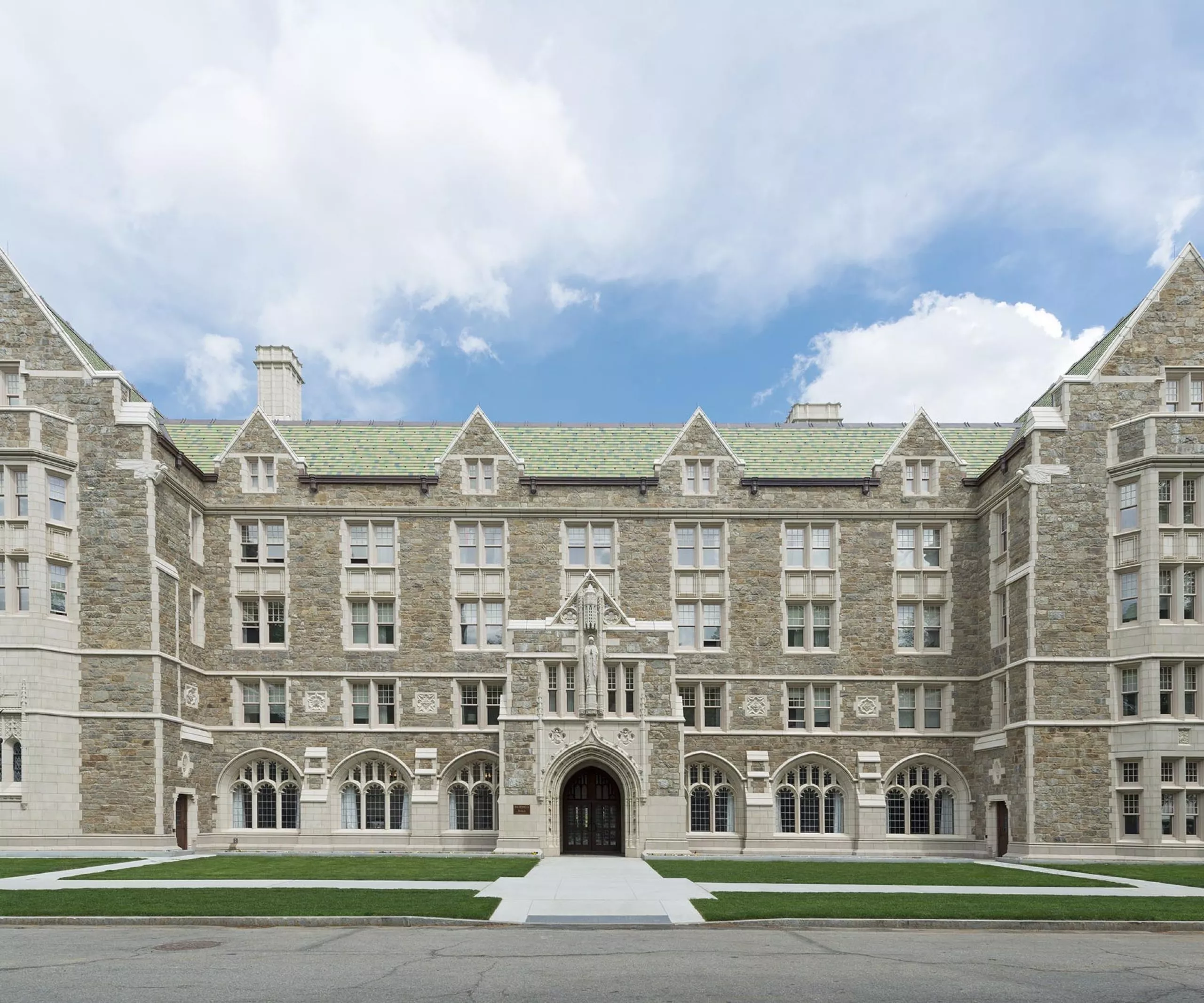 a large stone building with a green lawn with Boston College in the background