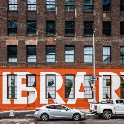 Exterior wall of Adams Street Library with a mural of the word Library on the wall