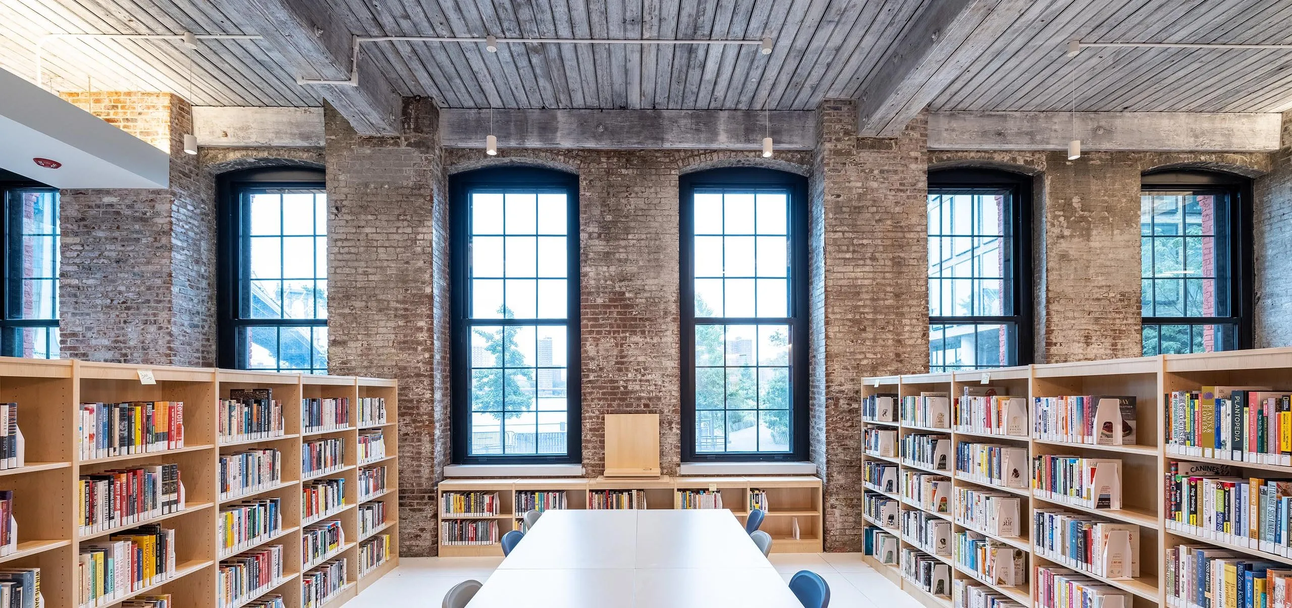 Bookshelves and a large table at the Adams Street Library