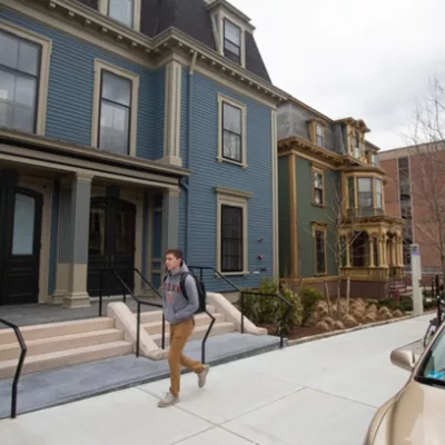 student walking outside in front of houses