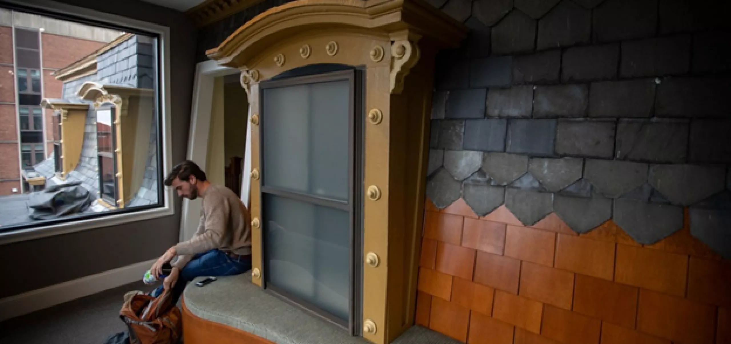 student sitting at giant windowsill display inside