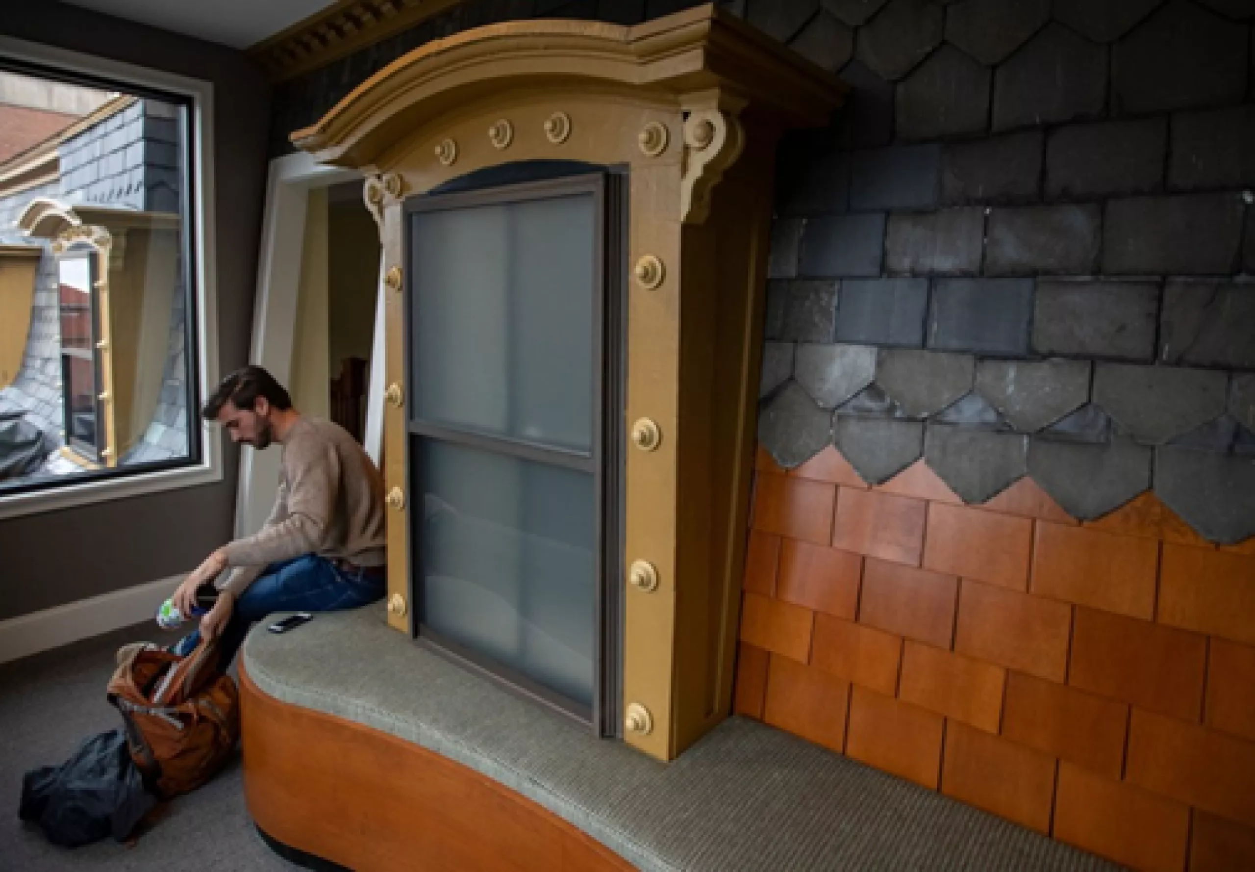 student sitting at giant windowsill display inside