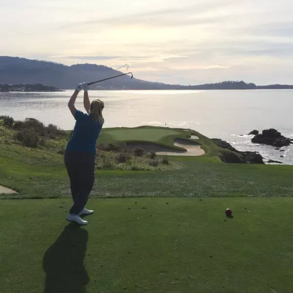 Kathryn Douglas hitting a golf ball with a landscape of the ocean in the background