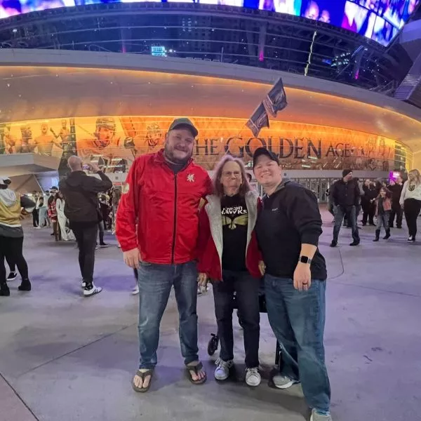 Eric Geisler with two other people at a hockey stadium