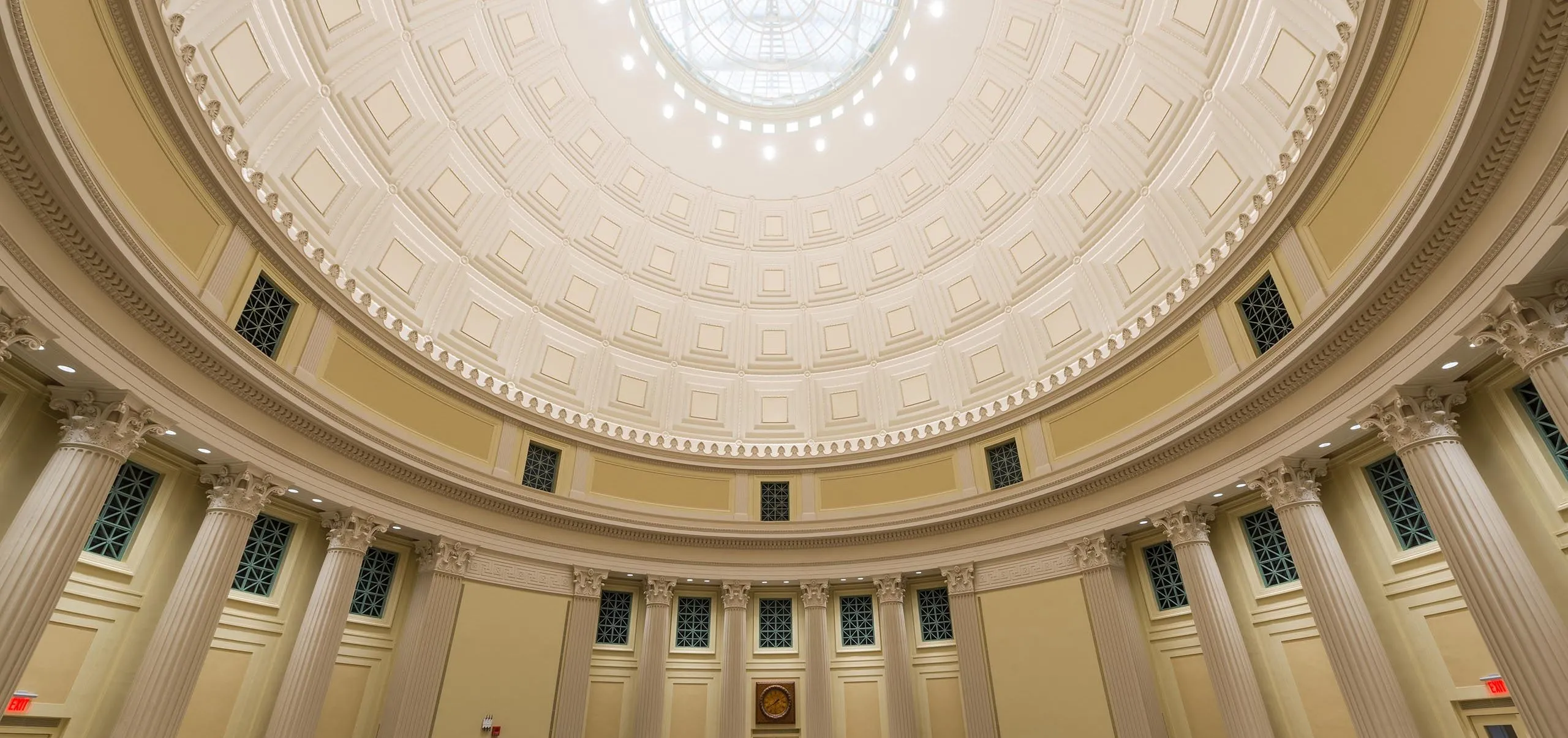 a room with a dome ceiling and tables and chairs with Federal Hall in the background