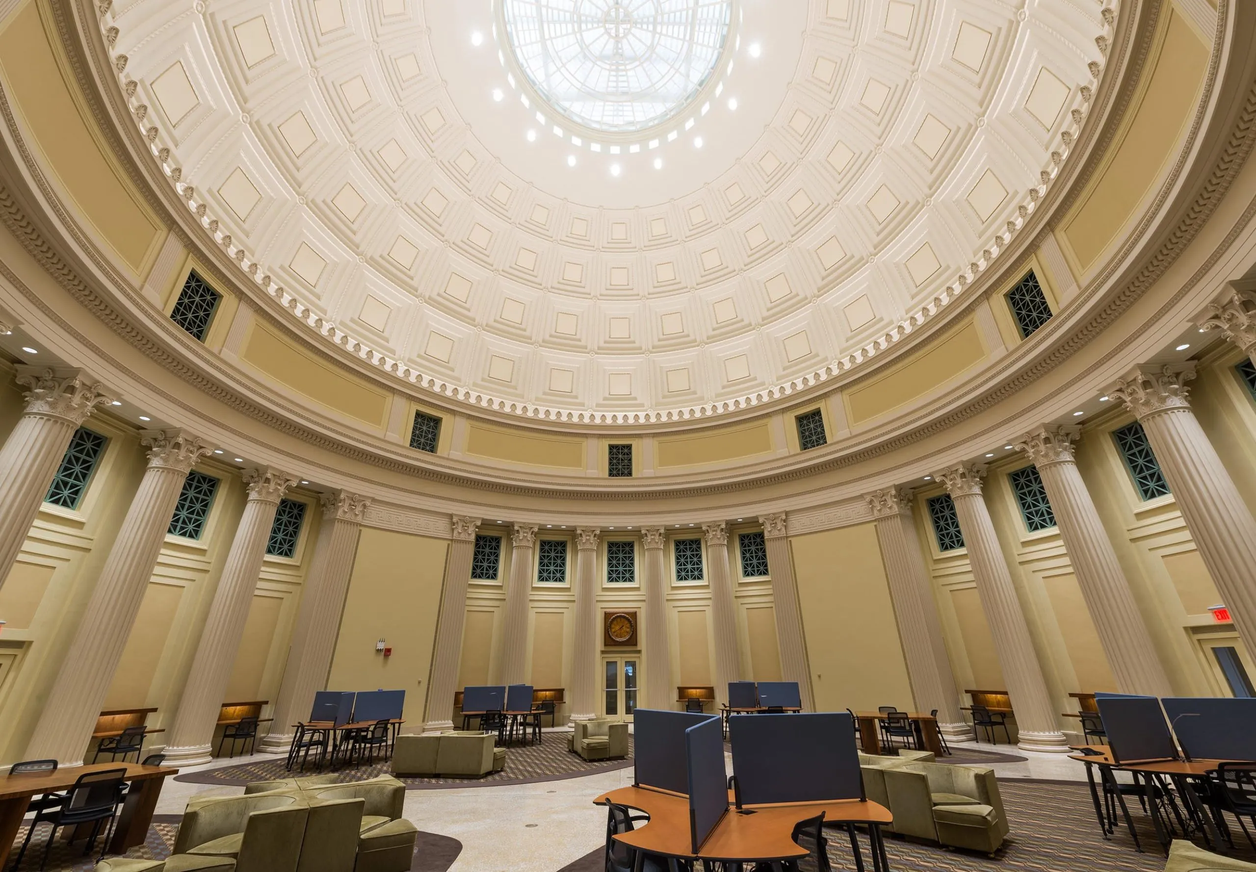 a room with a dome ceiling and tables and chairs with Federal Hall in the background