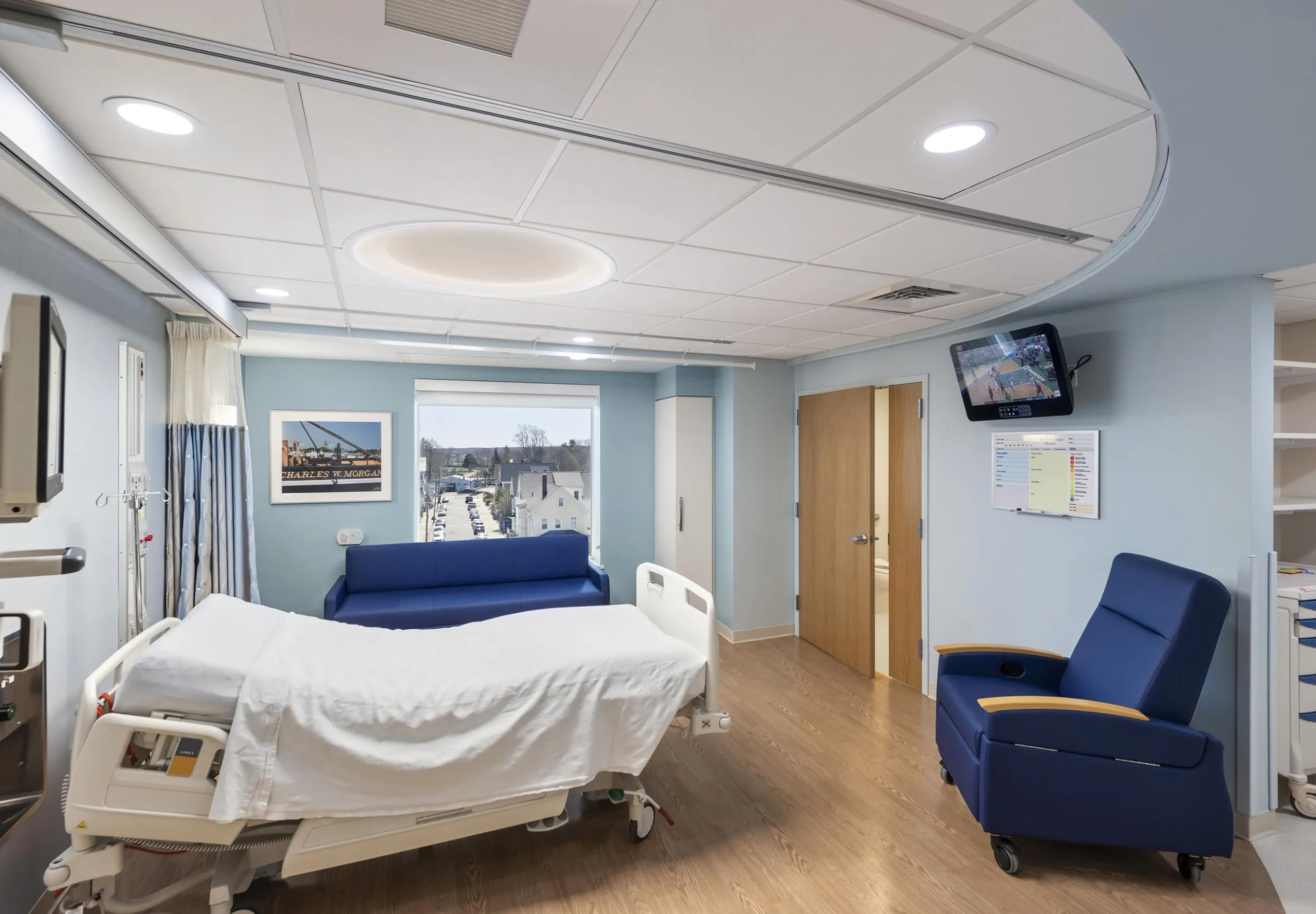 Interior view of a hospital room with a bed, blue couch and chair at St. Luke's Hospital