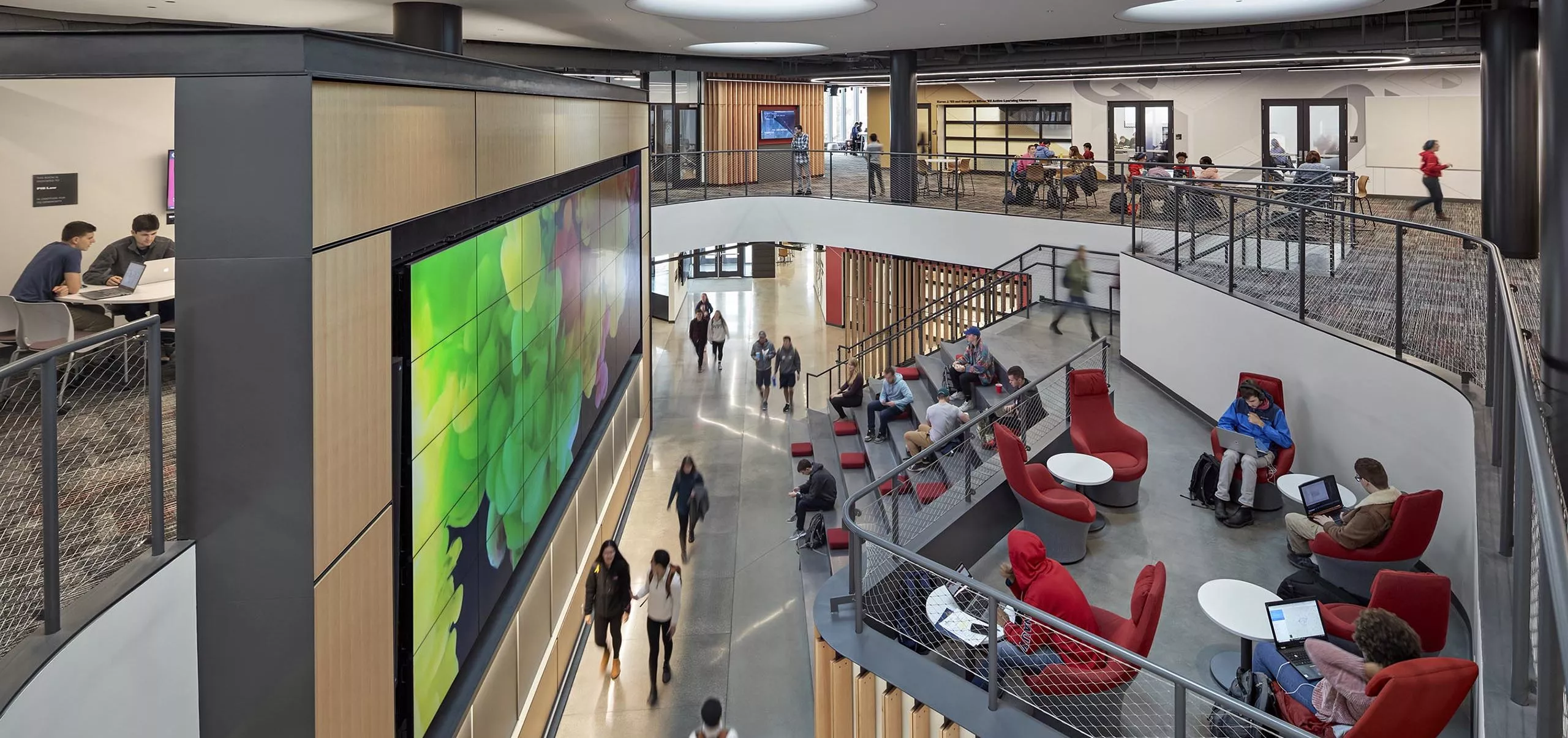 A group of people sitting on large stairs and walking in Innovation Studio & Messenger Residence Hall