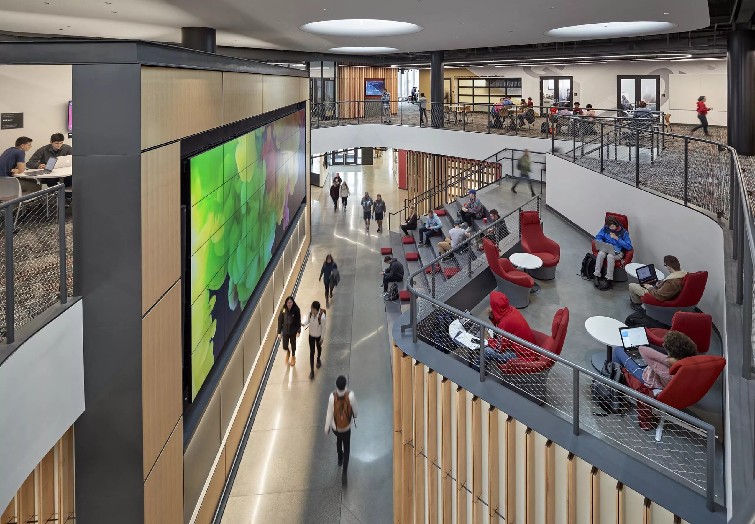 A group of people sitting on large stairs and walking in Innovation Studio & Messenger Residence Hall