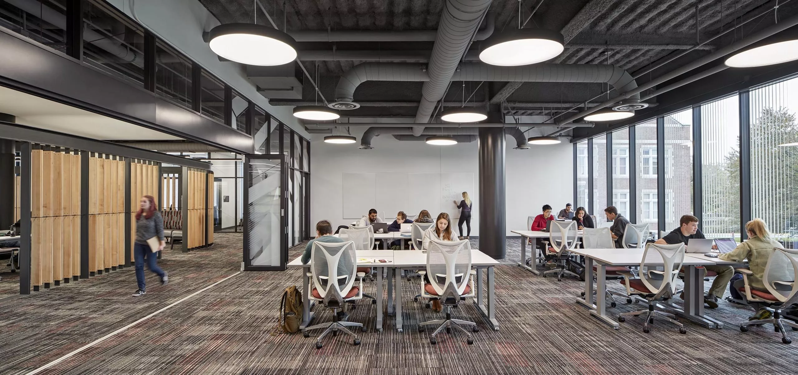 A group of people sitting at communal tables in Innovation Studio & Messenger Residence Hall