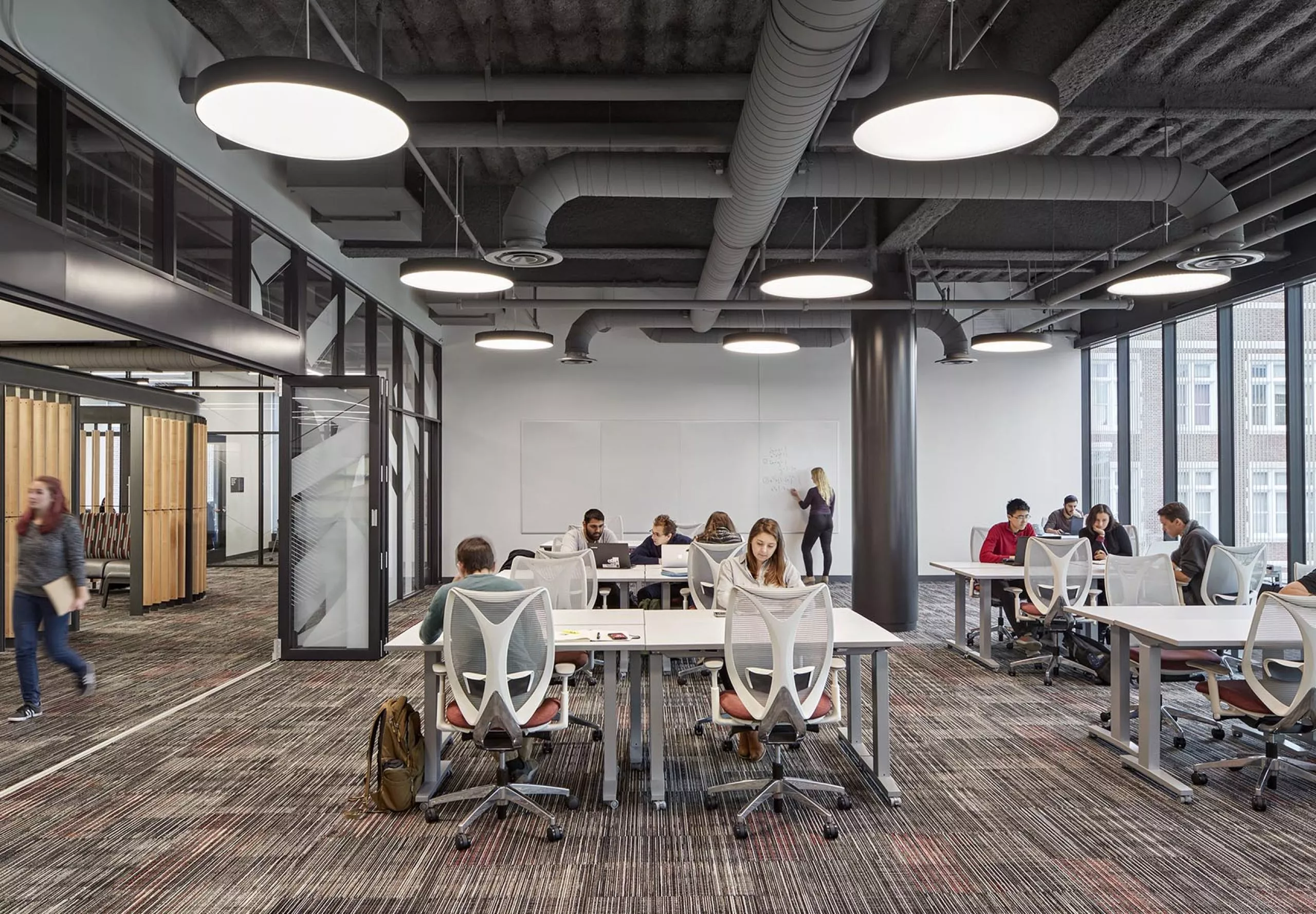 A group of people sitting at communal tables in Innovation Studio & Messenger Residence Hall