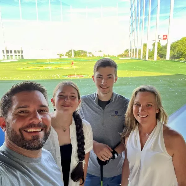 Chris Maury with a group of people at a golf putting green