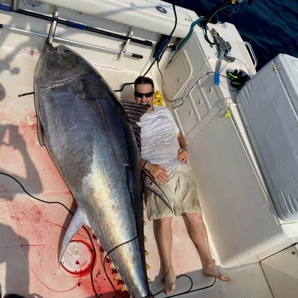 Roger Tougas in a boat laying next to a fish larger than him