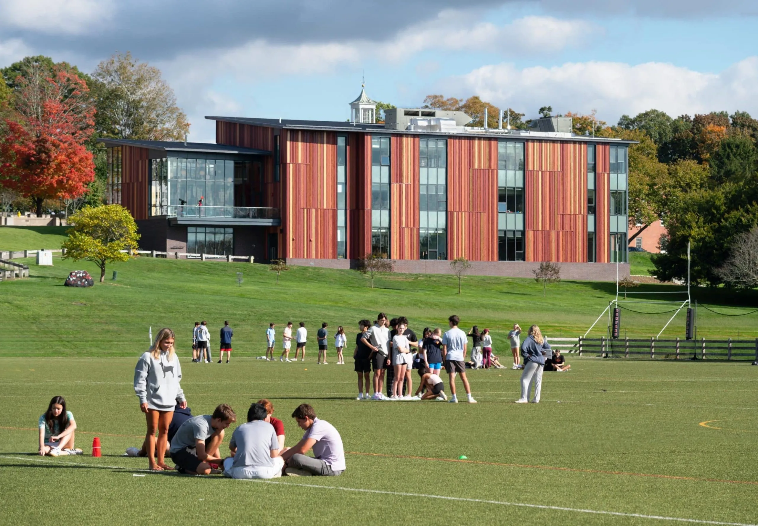 People standing in field with modern VISTA building in distance